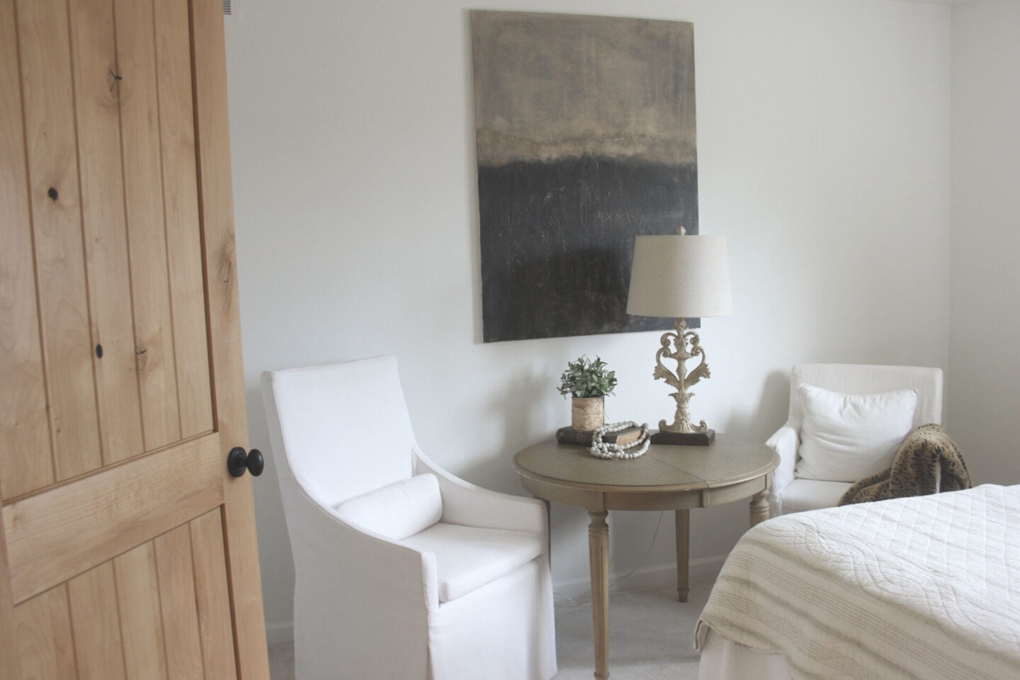 Rustic knotty alder door opens into white bedroom with Belgian style furniture and abstract painting by Hello Lovely Studio. #alderdoor #europeancountrydecor #hellolovelystudio