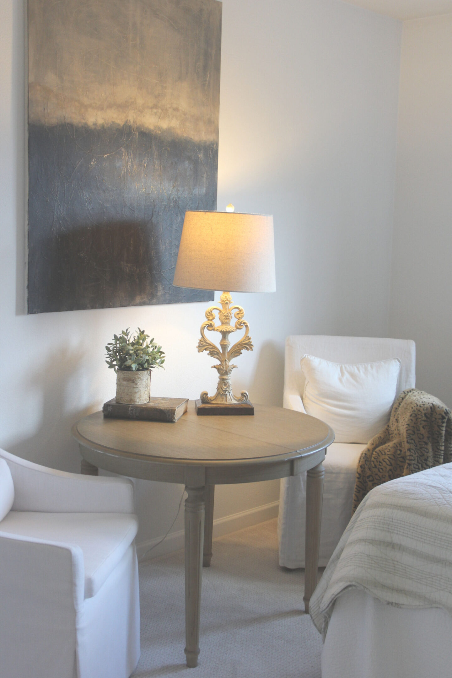 White linen slipcovered Belgian style chairs and a moody abstract painting in a bedroom by Hello Lovely Studio.