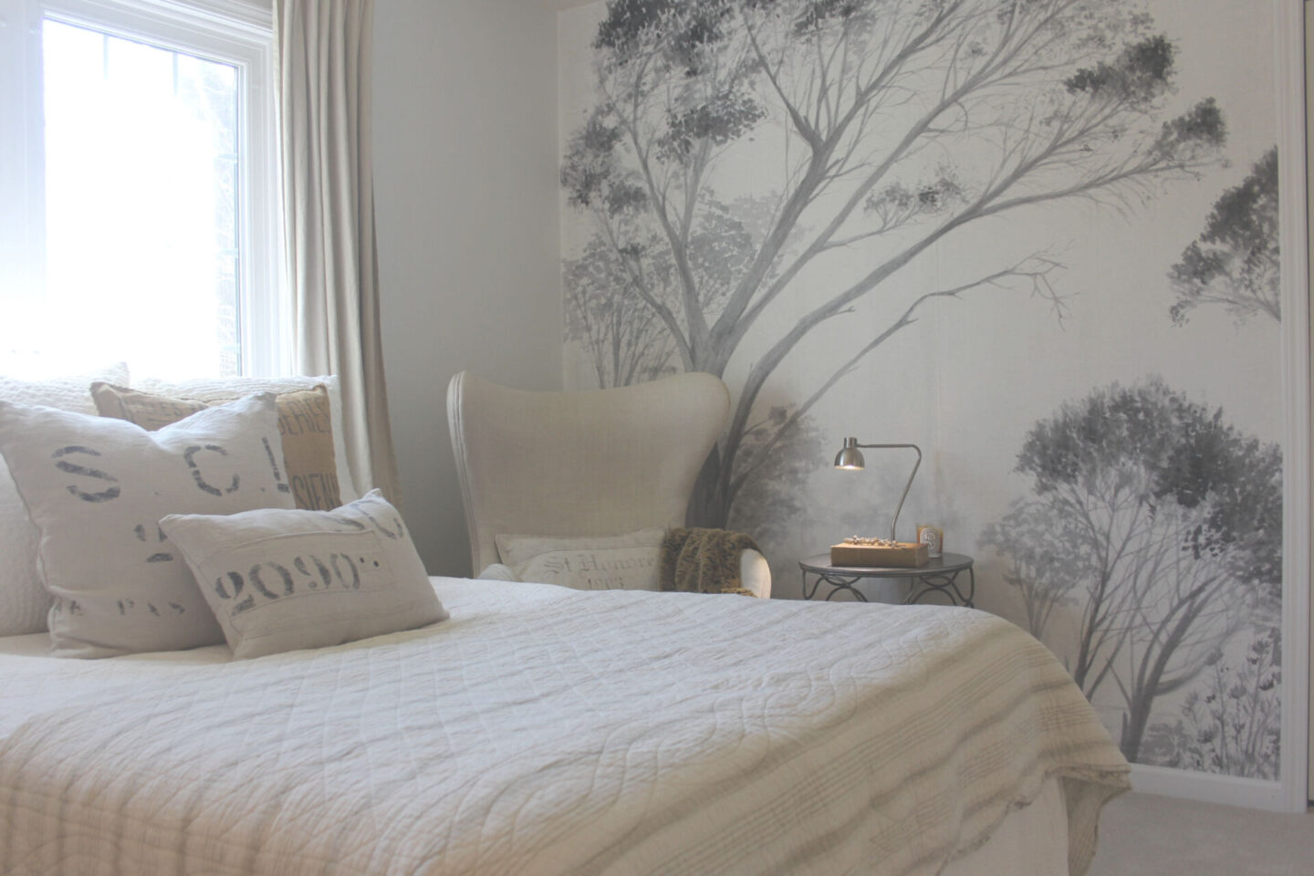 Subdued, understated, and serene, a tone on tone wall covering with gray trees sets a calm tone in a bedroom - Hello Lovely Studio. #wallcovering #photowall #treewallpaper #hellolovelystudio