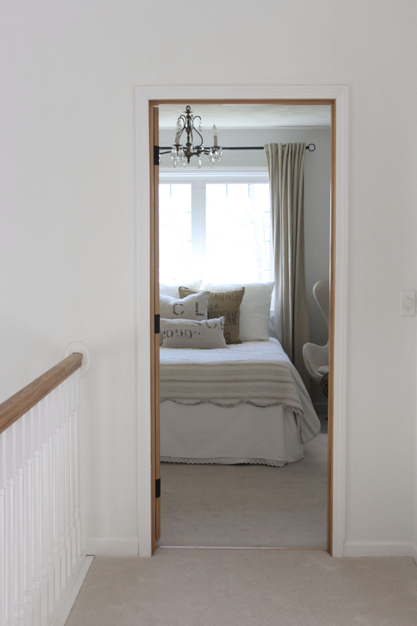 Hello Lovely's European country style bedroom with knotty alder door and walls painted BM White OC-151.