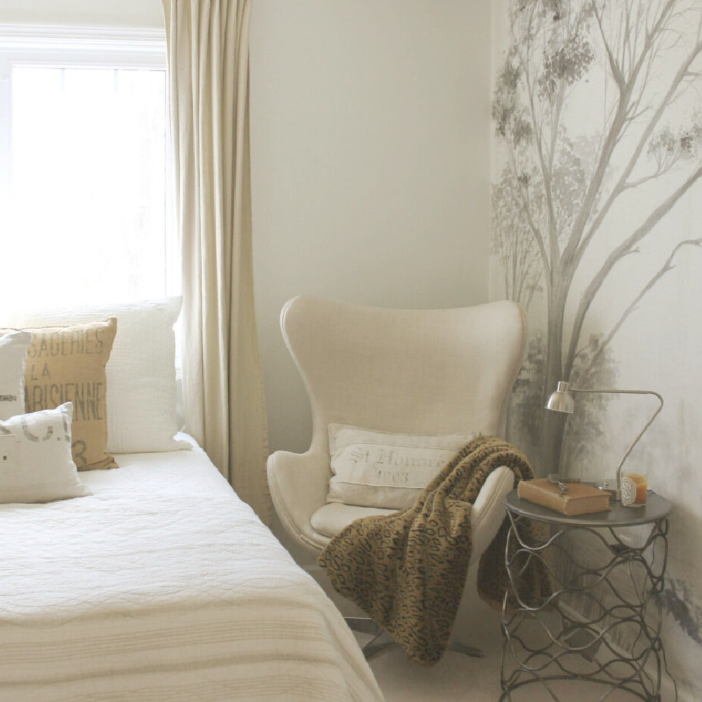 Beautiful grisaille mural wallpaper with trees in light grey on a white ground in a guest bedroom with neutral decor and egg chair - Hello Lovely Studio. #mural #muralwallpaper #grisaille