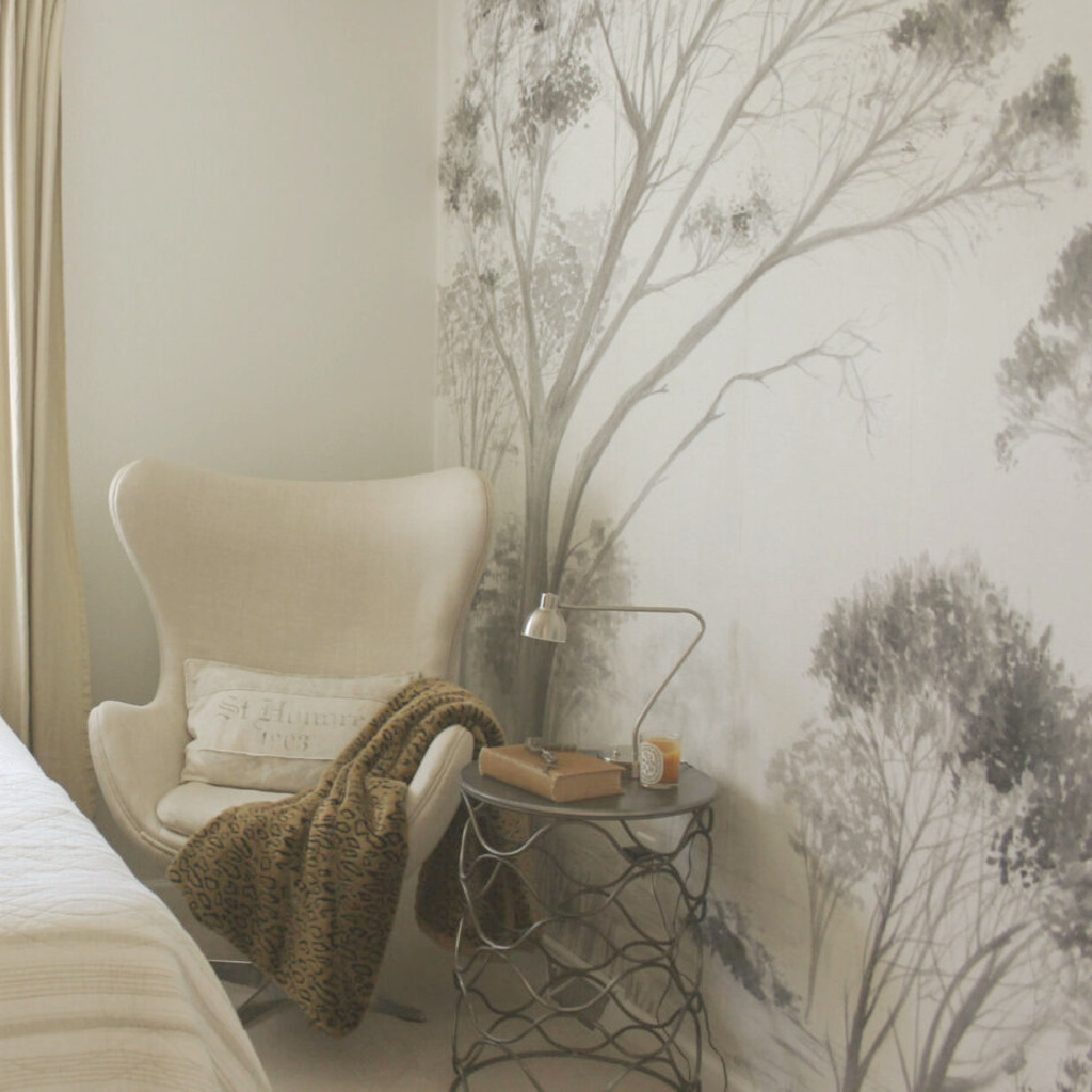 Beautiful grisaille mural wallpaper with trees in light grey on a white ground in a guest bedroom with neutral decor and egg chair - Hello Lovely Studio. #mural #muralwallpaper #grisaille