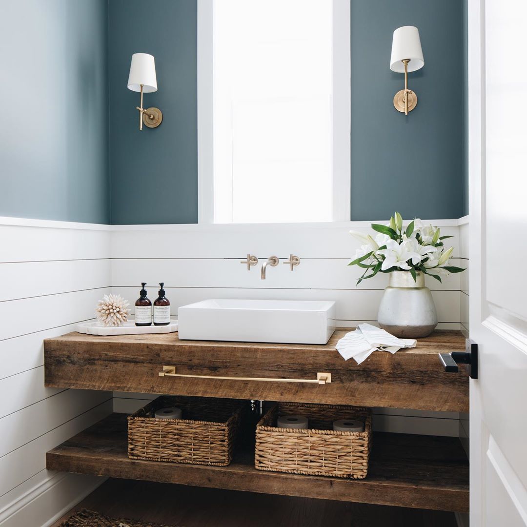 Modern farmhouse bathroom with gorgeous custom rustic wood vanity, rectangle fireclay farm vessel sink, wall mount faucet, shilap backsplash, and moody blue grey walls. Julie Howard for Timber Trains Homes (Western Springs, IL). Photo by Stoffer Photography Interiors #bathroomdesign #modernfarmhouse #bluegrey