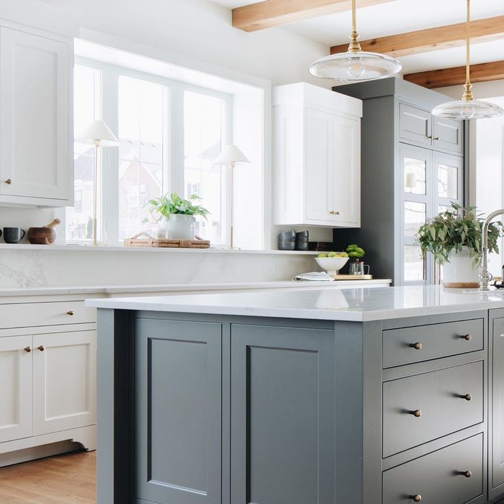 Gorgeous custom kitchen with blue grey island, white cabinets, beams, and Caesarstone counters including unique ledge and backsplash. Julie Howard for Timber Trails Homes (Western Springs, IL). Photo by Stoffer Photography. #kitchendesign #bluegrey #kitchenisland #ceilingbeams #darkgray 