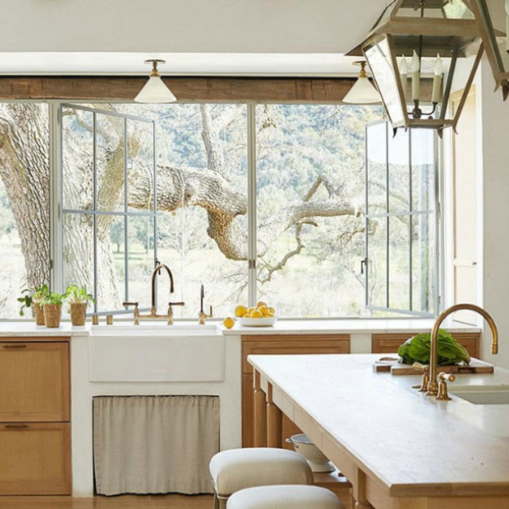 Patina Farm kitchen with white oak cabinets, farm sink, and steel windows - Giannetti Home and Brooke Giannetti. #patinafarm #frenchfarmhouse #farmhousekitchen #whiteoakcabinets #farmsink #lanternpendant #brookegiannetti