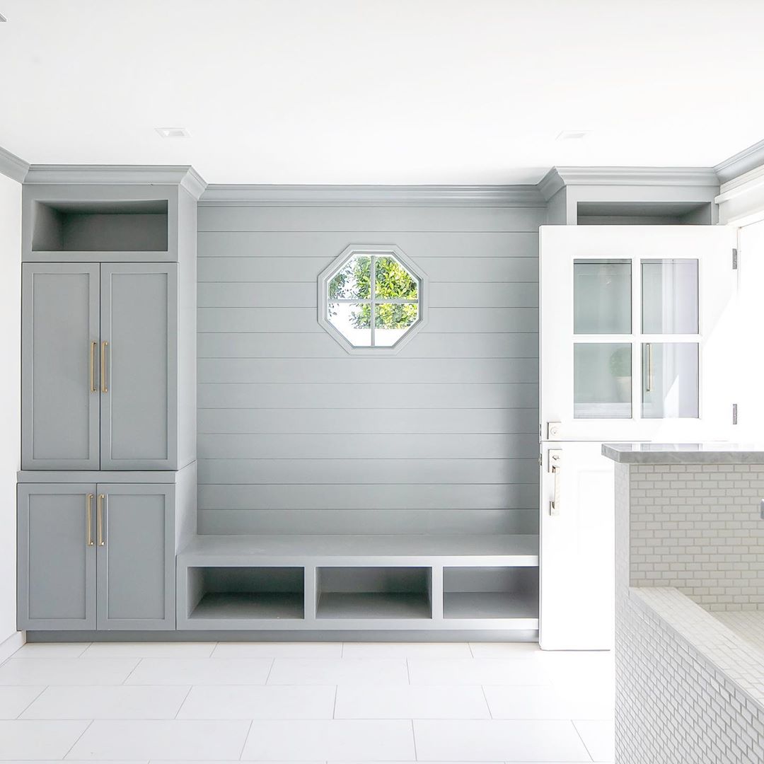 Lovely serene light grey blue mud room with custom built ins, octagon window, shiplap, and Dutch door. Design by AGK Design Studio; Builder: The Meter Co. #mudroom #interiordesign #bluegreypaint #dutchdoor #octagonwindow