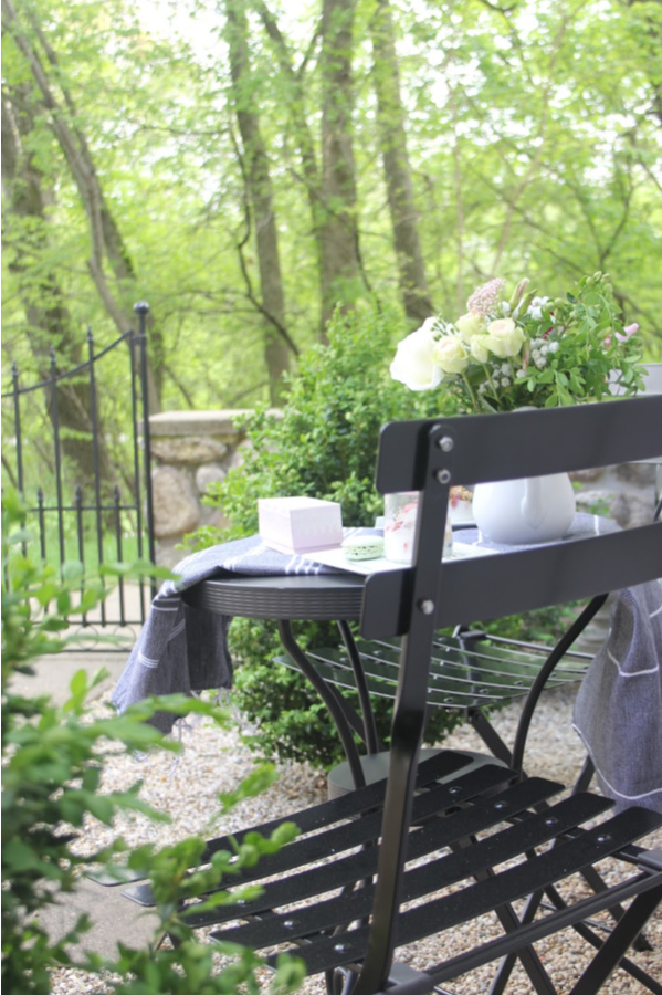 Lush green garden and a black French bistro set in my romantic courtyard. #hellolovelystudio #frenchcountry #bistrochairs #patiofurniture #romantidecor #outdoordecor