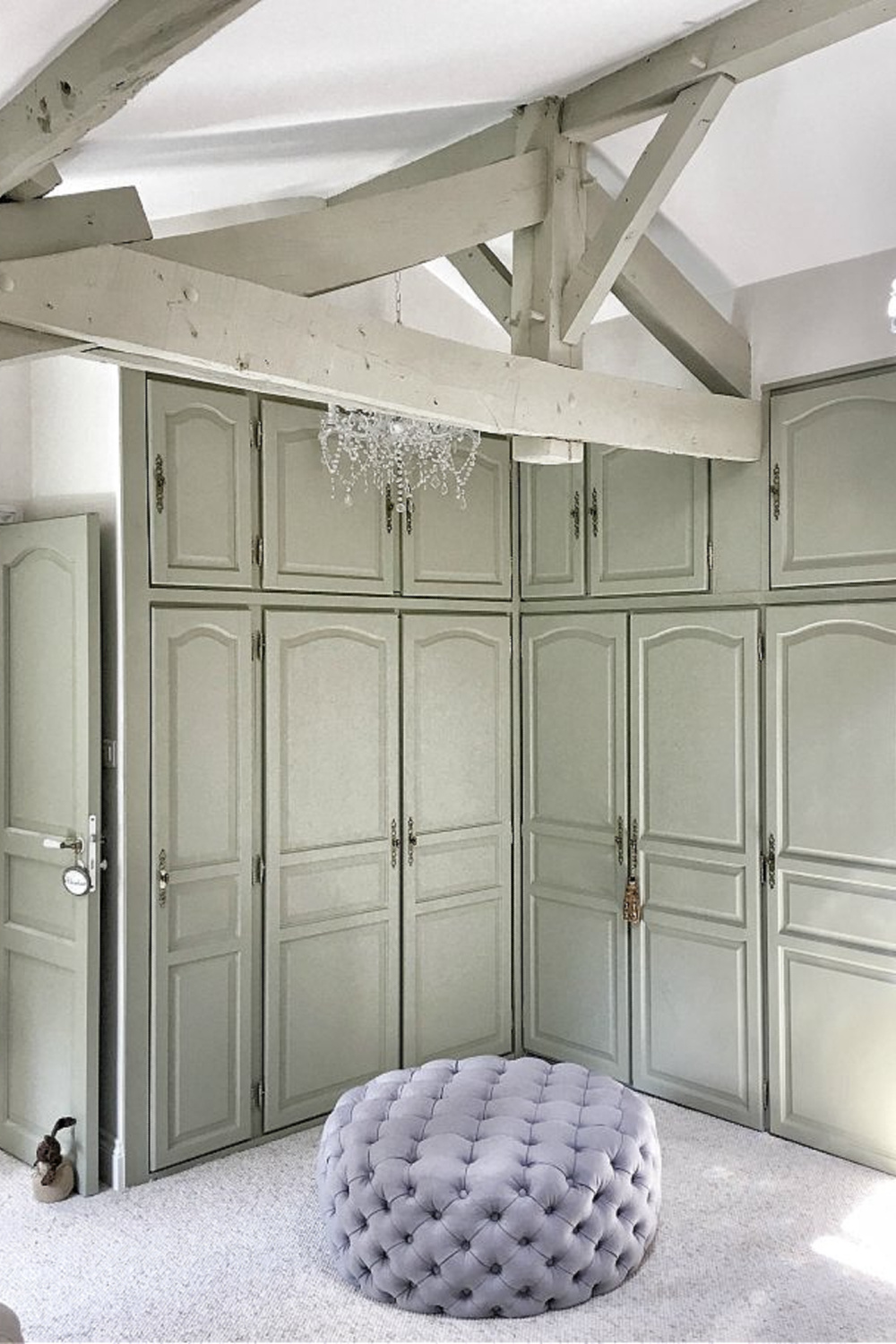 Grand candle style crystal chandelier and built-ins in a French bedroom with tufted ottoman.  You'll love this photo gallery and house tour of a home near Bordeaux, France. #vivietmargot #frenchfarmhouse #rusticdecor #countryfrench #interiordesign #bedroomdecor