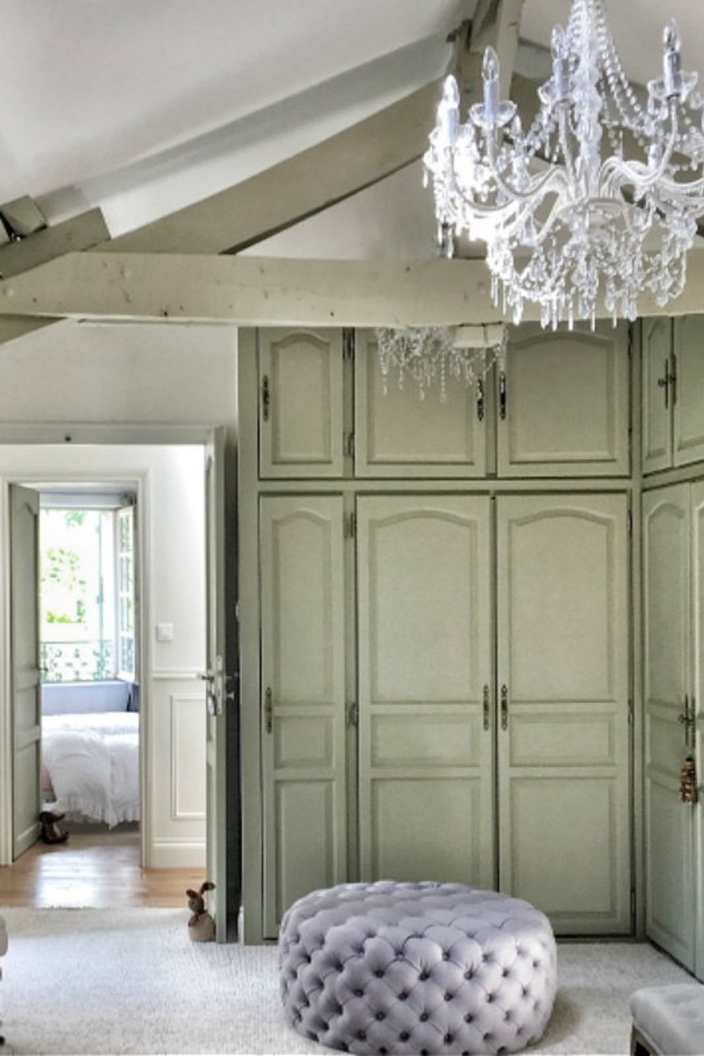 Round tufted ottoman in dressing area of bedroom in a farmhouse in France.  You'll love this photo gallery and house tour of a home near Bordeaux, France. #vivietmargot #frenchfarmhouse #rusticdecor #countryfrench #interiordesign #bedroomdesign #builtins #tuftedottoman