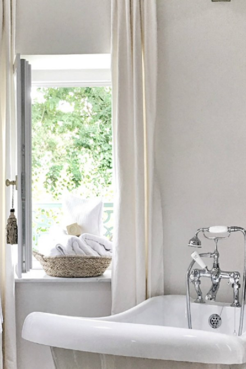 Detail of clawfoot tub near open window in a farmhouse in France.. You'll love this photo gallery and house tour of a rustically elegant farmhouse near Bordeaux by Vivi et Margot. #bathroomdesign #clawfoottub #frenchcountry