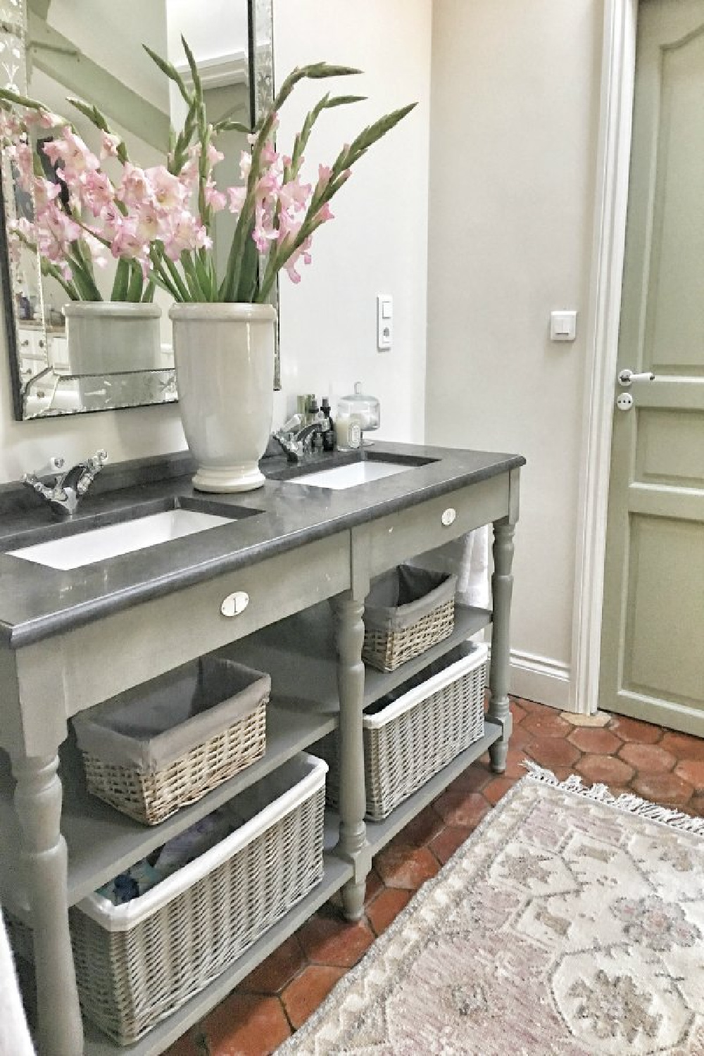 Double vanity with open shelving in romantic bath. Beautiful French farmhouse design inspiration and house tour (Vivi et Margot). #bathroomdecor #interiordesign #frenchfarmhouse #bathroomvanity