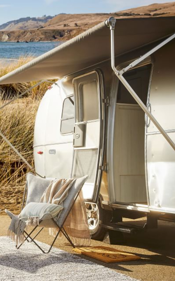 Butterfly chair outside Airstream. Airstream at Pottery Barn is a lovely collection of whimsical and happy camper decor whether we have a vintage camper to put in or not! #airstream #potterybarn #happycamper #whimsicalgifts #vintagecamper #homedecor