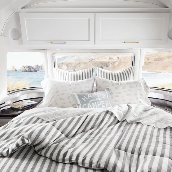 Stripe bedding and pillows. Airstream at Pottery Barn is a lovely collection of whimsical and happy camper decor whether we have a vintage camper to put in or not! #airstream #potterybarn #happycamper #whimsicalgifts #vintagecamper #homedecor #bedding