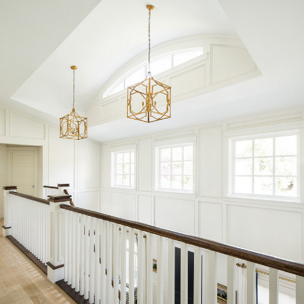 Architecturally magnificent upper stair landing with wood flooring, classic paneling, brass pendants, and an abundance of natural light. Design by The Fox Group. Come see more Timeless Interior Design Ideas. #staircase #classicarchitecture #thefoxgroup