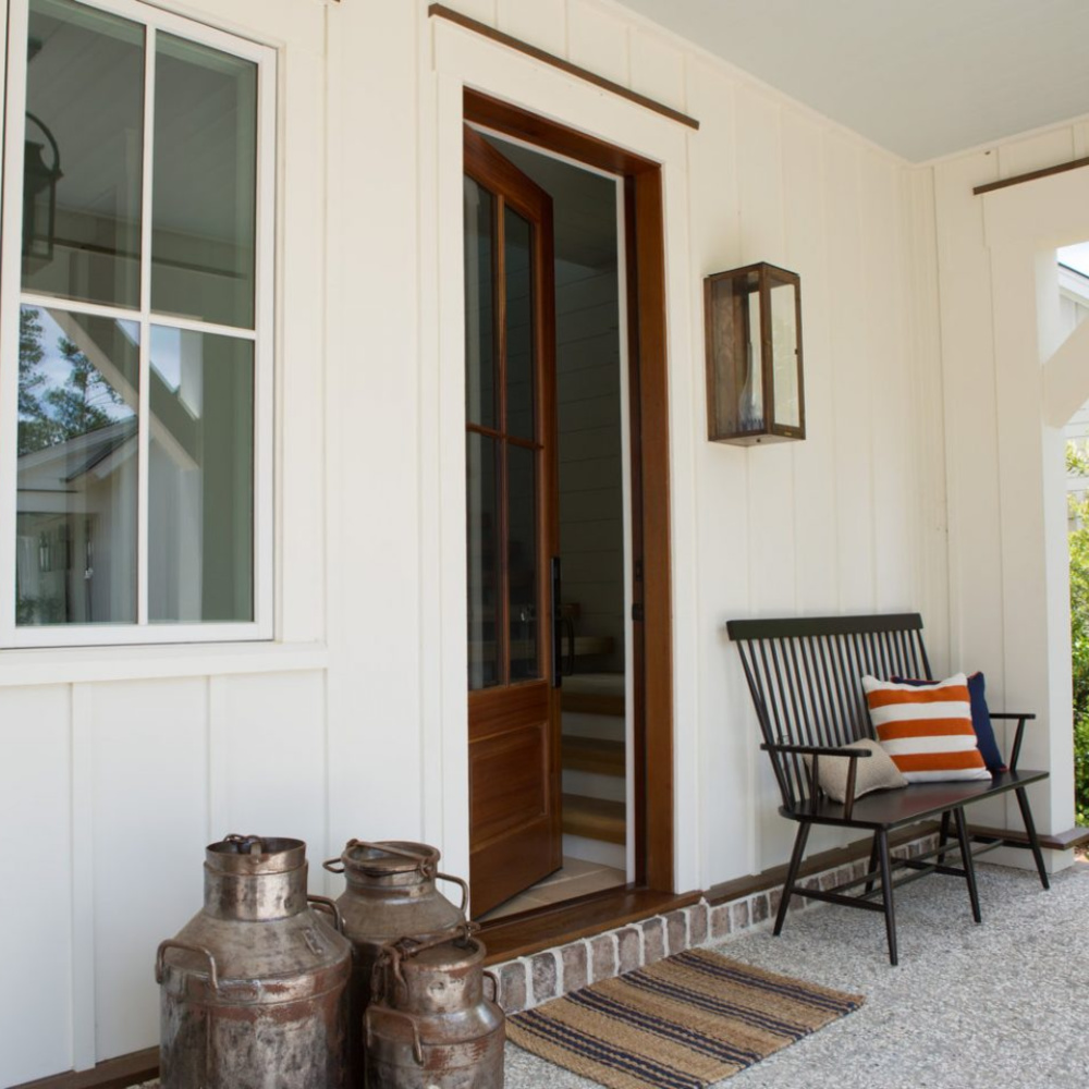 Modern farmhouse front porch of a South Carolina coastal cottage with bench and milk cans. #frontporch #cottagestyle #coastalcottage