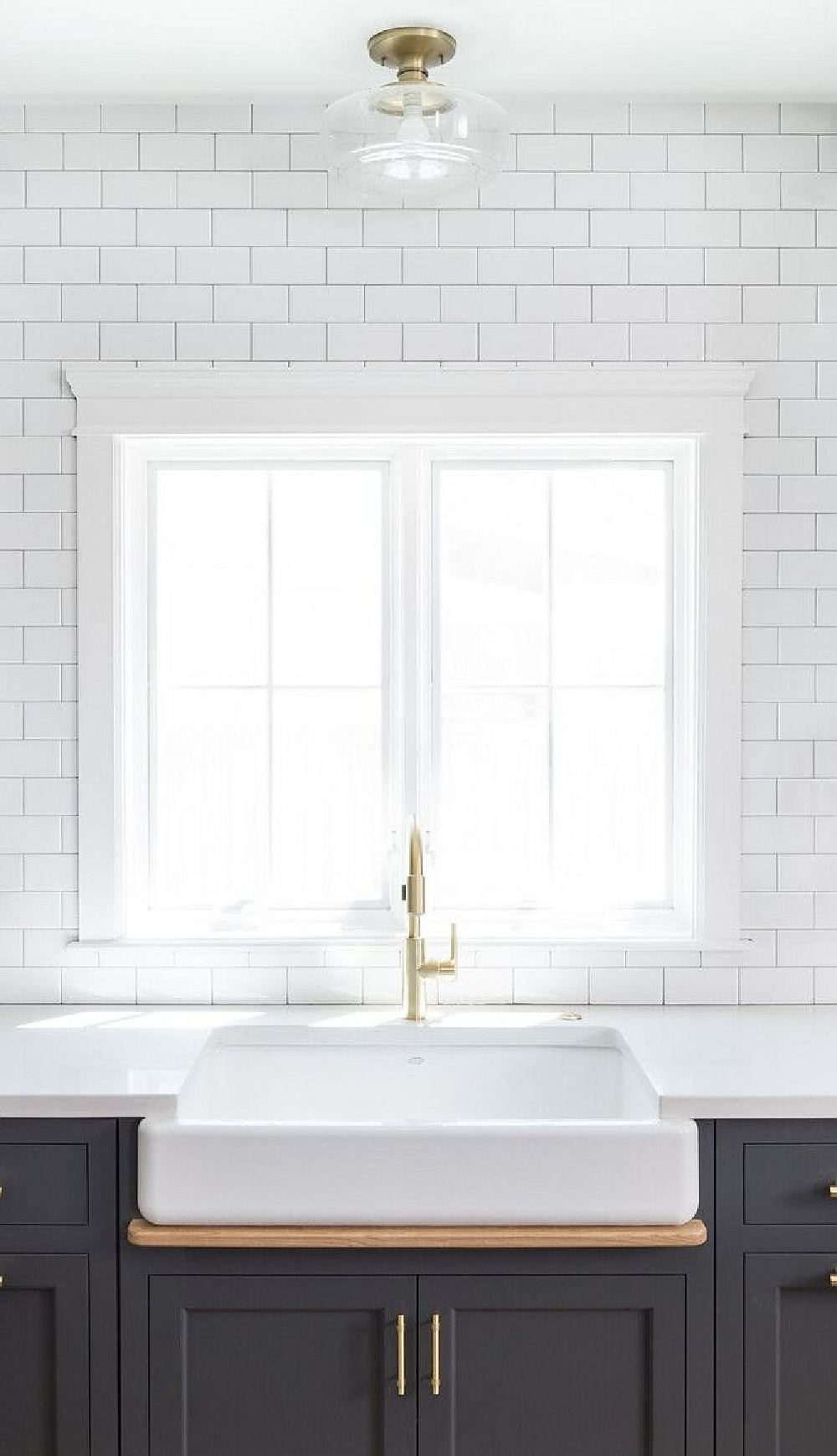 Subway tile accent wall in modern farmhouse kitchen by The Fox Group. Farm sink and dark grey painted cabinetry. Come be inspired by more Timeless Interior Design Ideas, Paint Colors & Furniture. #thefoxgroup #kitchendesign #modernfarmhousekitchen #benjaminmoorecheatingheart #greycabinets #subwaytile