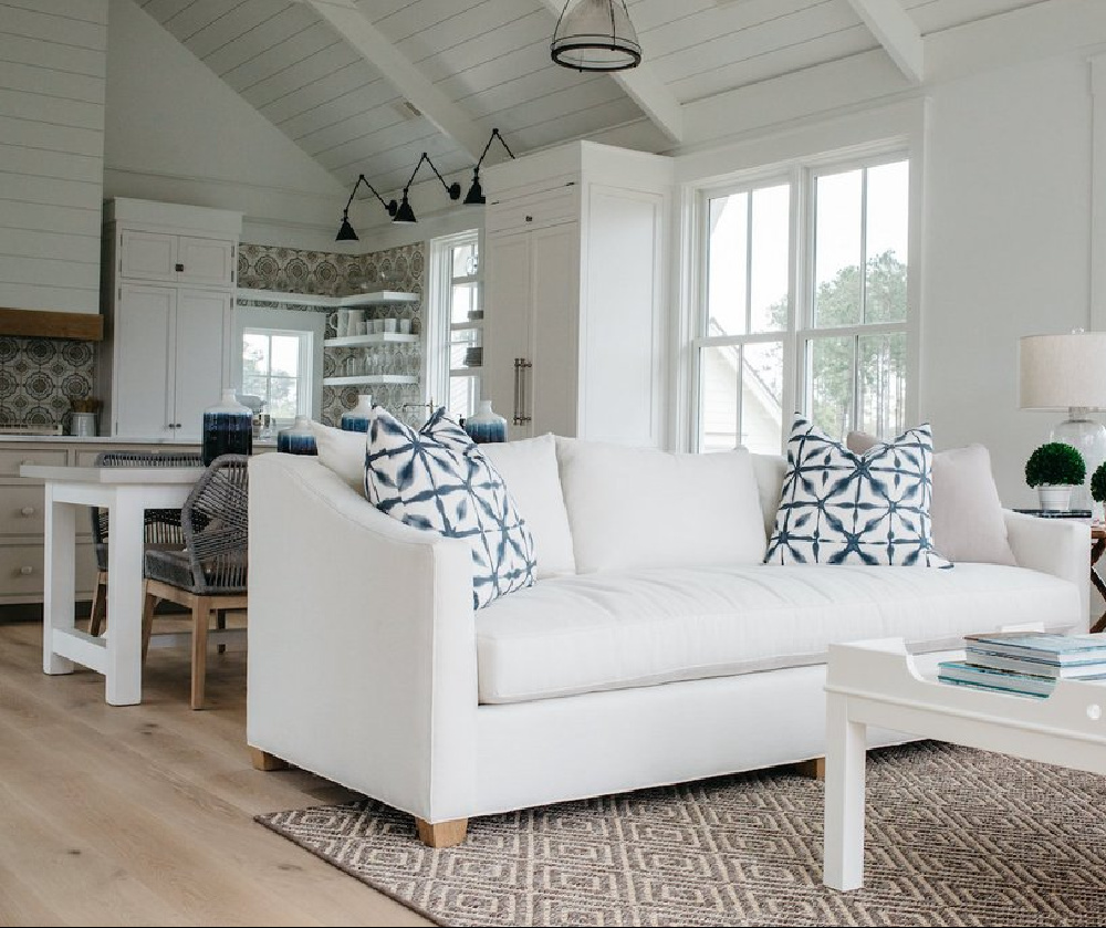 White great room, dining area, and kitchen in a board and batten coastal cottage in Palmetto Bluff. Modern farmhouse interior design with blue, white, and natural materials by Lisa Furey. #greatroom #coastalstyle #blueandwhite #interiordesign