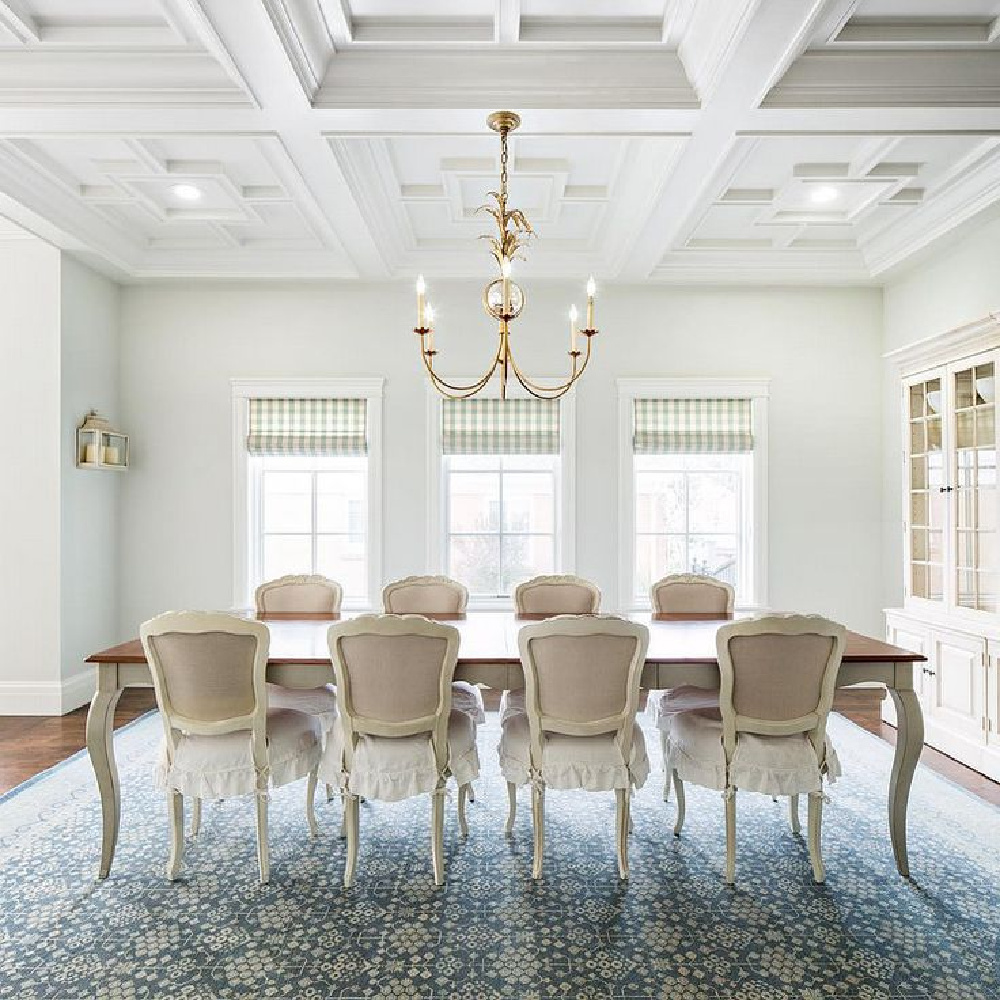 Breathtaking dining room design by The Fox Group. French Bergere chairs surround a French country dining table. Check pattern on roman blinds and dramatic coffered ceiling. Muted palette and serene mood. #thefoxgroup #diningroom #Frenchcountry #timless