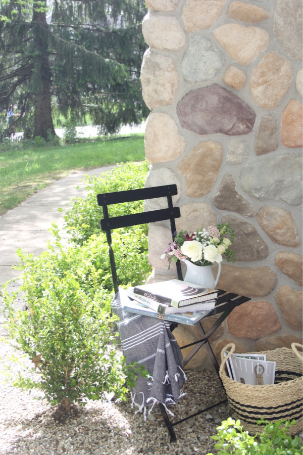 French bistro chair and stripe Turkish throw tucked in a corner of my garden to invite relaxation and reading (cookbooks are my idea of relaxation!). #hellolovelystudio #frenchcountry #bistrochair #turkishthrow #turkishtowel #outdooroasis #romanticgarden #outdoordecor #bistrochairs