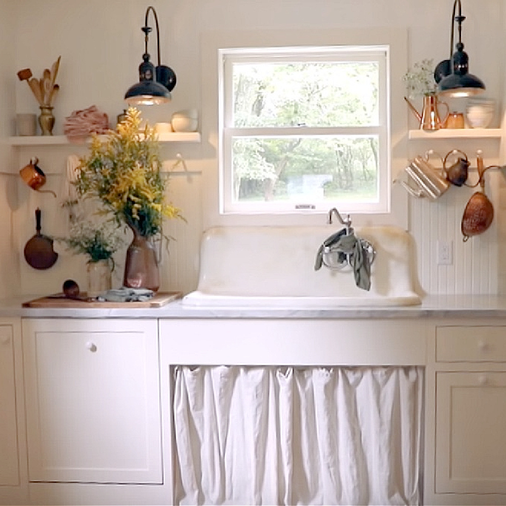 Rustic white cottage kitchen with vintage charm by Leanne Ford in a renovation on Restored by the Fords. #leanneford #rusticdecor #kitchendesign #vintagestyle #farmsink