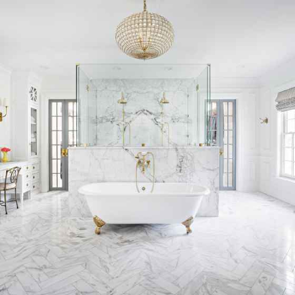 Luxurious marble bathroom with clawfoot tub, herringbone marble floor, and symmetrical French doors. Design by The Fox Group. #luxuriousbathroom #bathroomdesign #frenchdoors #thefoxgroup #clawfoottub