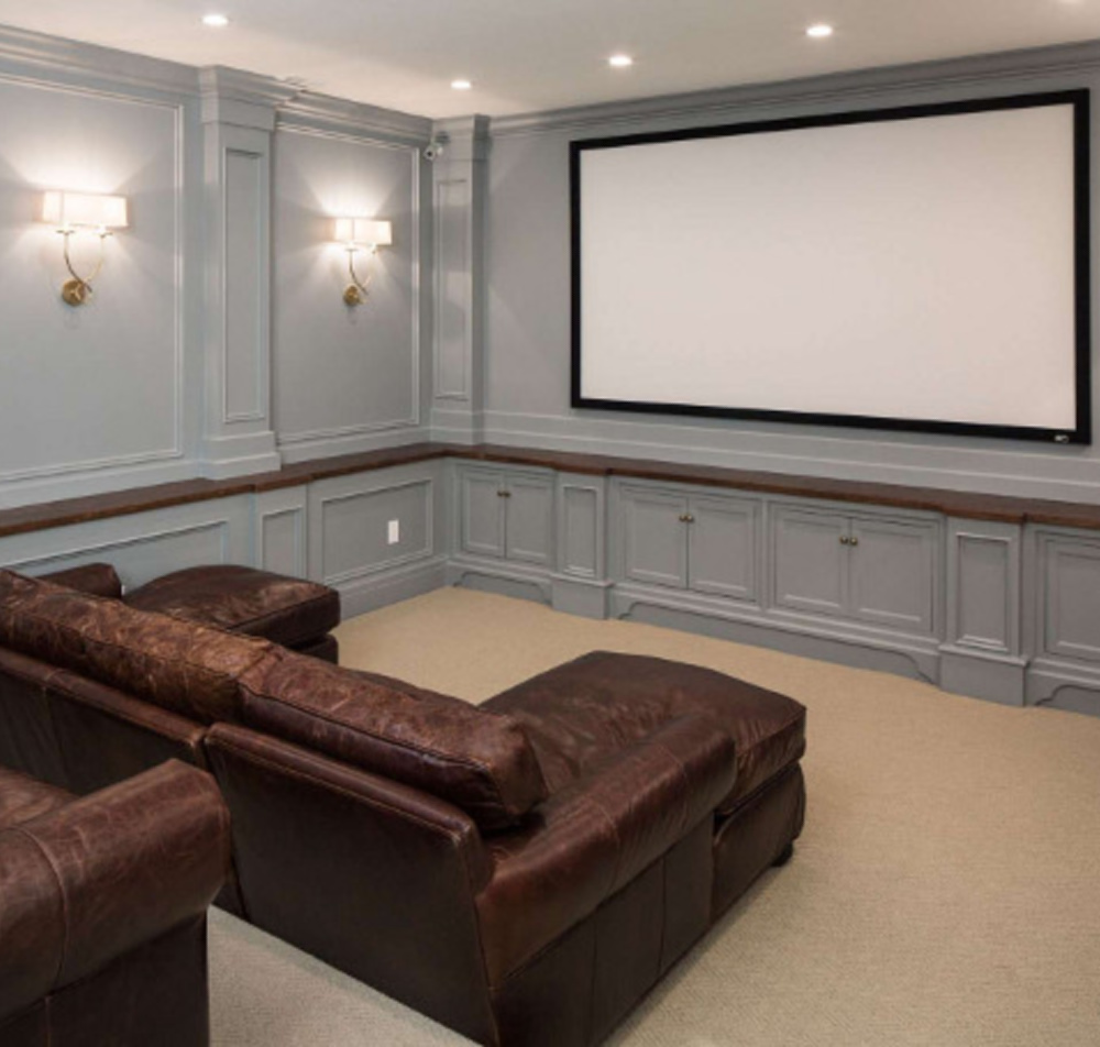 Grey painted paneling in an elegant media room with brown leather sofas by The Fox Group. #mediaroom #thefoxgroup #paneling #greypaneling #brownleather