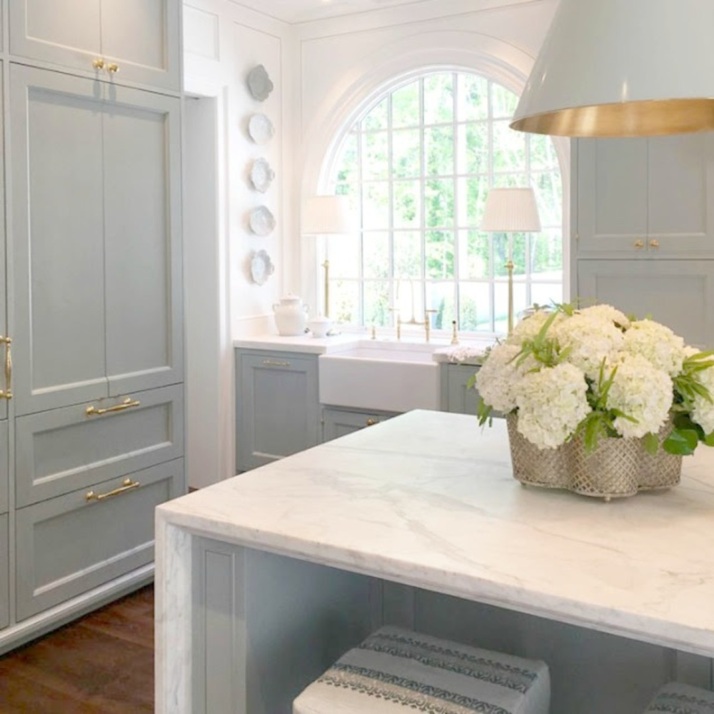 Elegant and luxurious kitchen with Farrow & Ball Light Blue cabinets, Sherwin Williams Alabaster on walls, and design by Design Galleria and Lauren DeLoach. Come explore Interior Designers Favorite White Paint Colors for ideas, photos, and inspiration.