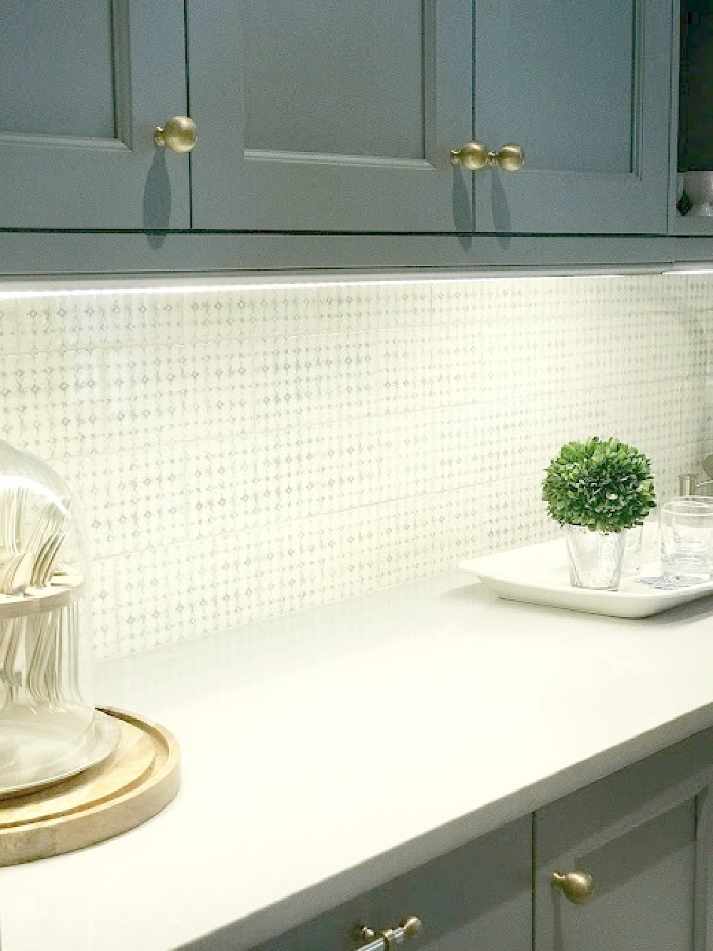 Detail of handmade backsplash and blue painted cabinetry in tan elegant raditional kitchen pantry with brass hardware. #bluekitchen #farrowandballlightblue #timelesskitchen #kitchendesign #traditionalkitchen