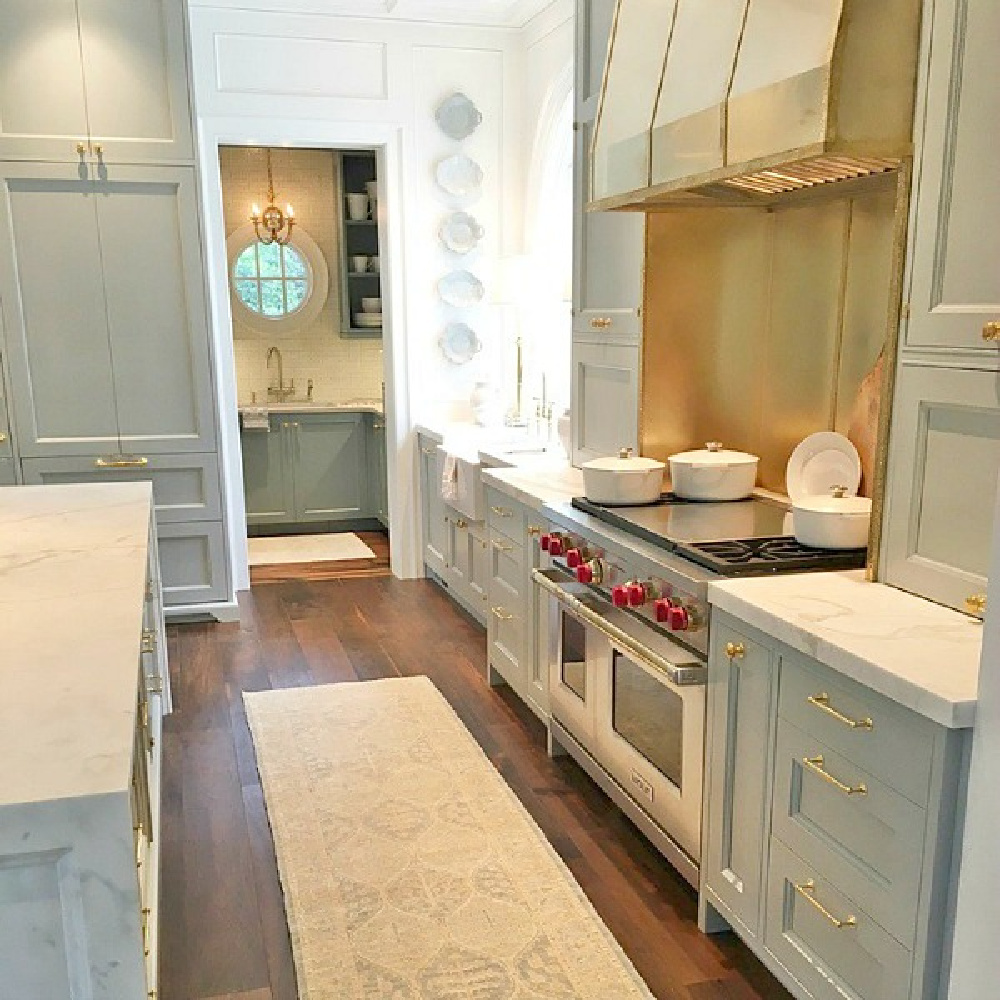 Magnificent Matthew Quinn kitchen in Atlanta with waterfall marble countertop, light blue, and brass accents. #bluekitchen #brasshardware #farrowandballlightblue #timelesskitchen #kitchendesign #traditionalkitchen #interiordesign