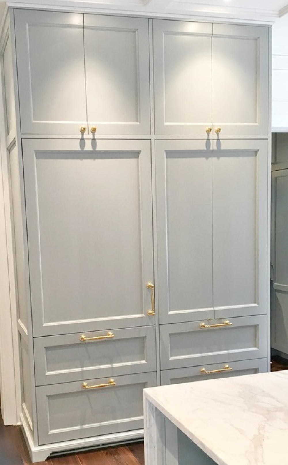 Custom cabinetry in a designer showhouse kitchen is painted Farrow & Ball Light Blue and is enhanced by brass hardware. #bluekitchen #farrowandballlightblue #timelesskitchen #kitchendesign #traditionalkitchen