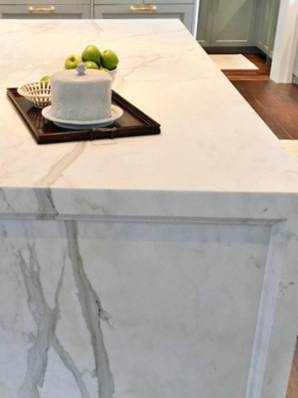 Detail of marble waterfall island countertop by Levantina in an Atlanta Showhouse kitchen with light blue cabinets. #bluekitchen #farrowandballlightblue #timelesskitchen #kitchendesign #traditionalkitchen