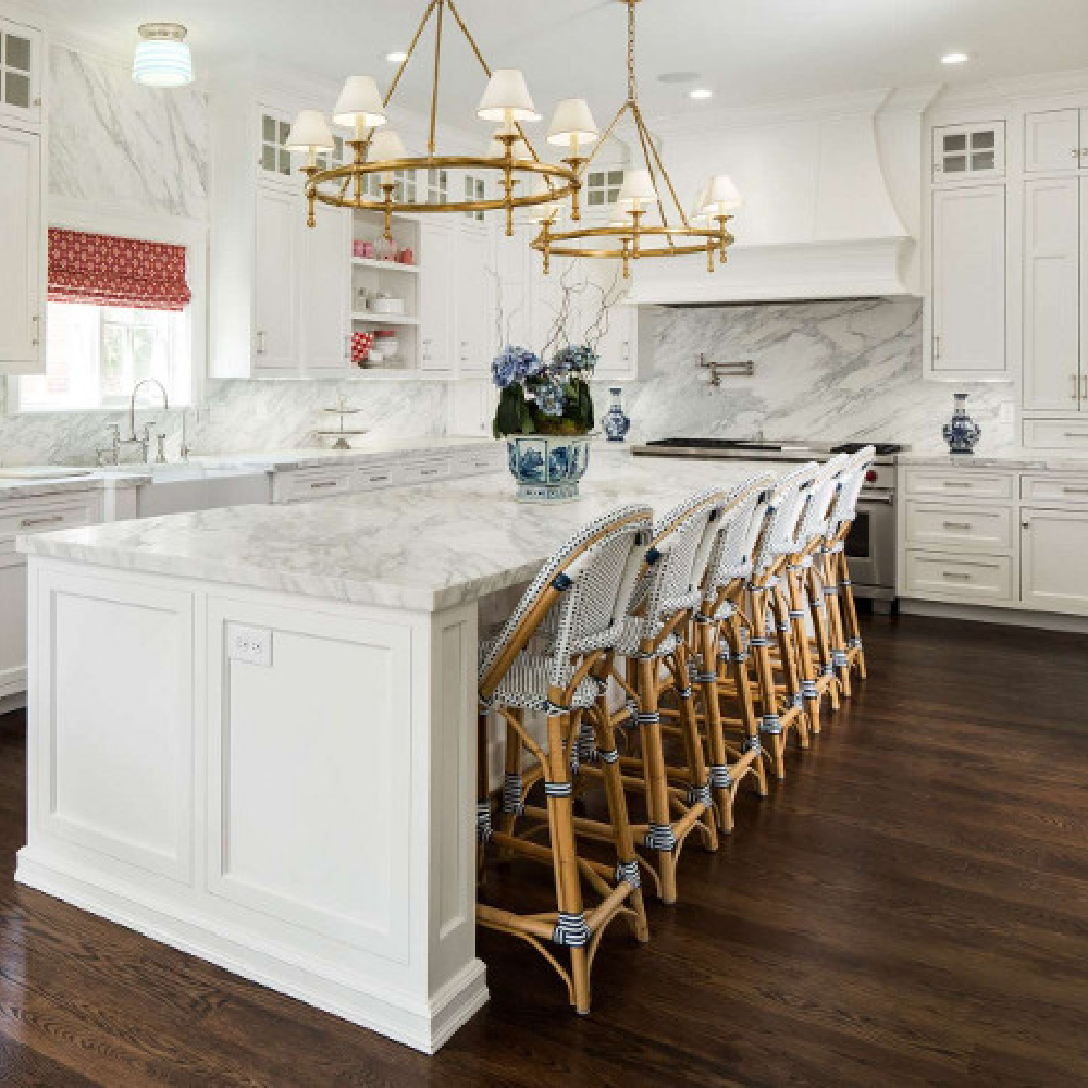 Luxurious kitchen by The Fox Group with Parisian bar stools, ring style chandeliers over island, and white cabinetry. #thefoxgroup #kitchendesign #timelessdesign