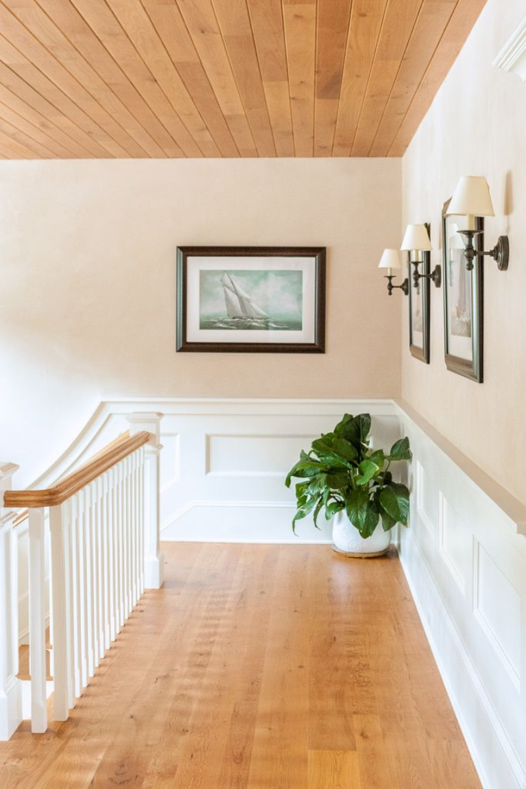 Beautiful wide plank flooring (white oak) on a staircase landing with paneled wainscot and pale peachy walls. #whiteoak #flooring #hardwoodfloor #carlisle #woodplankfloors #interiordesign #carlisle #staircase