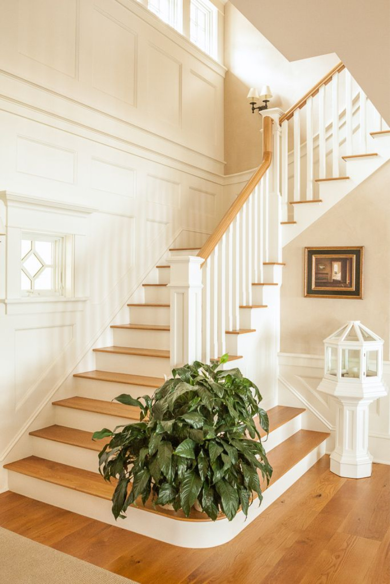 Stunning white oak wide plank flooring on a staircase in a grand coastal style home with white trim. #flooring #interiordesign #whiteoak #staircase #wideplankfloors #hardwoodfloor #carlisle #coastalstyle