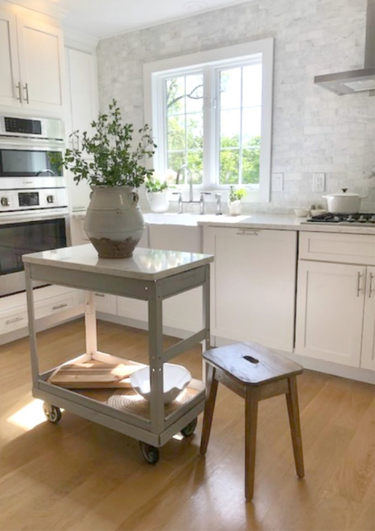 Hello Lovely Studio's serene white kitchen with vintage steel cart repurposed as a work table. #hellolovelystudio #whitekitchens #modernfarmhouse #coastal #shakerkitchen #vintagecart #worktable