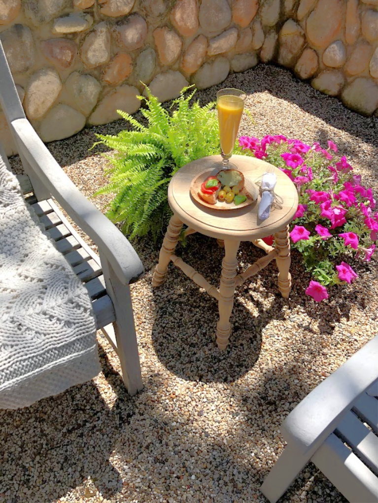 Savory snacks on a disposable plate made from palm leaves upon a rustic wood stool used as side table in our French inspired courtyard - Hello Lovely Studio. #hellolovelystudio #frenchcountry #courtyard #summergarden #rusticstool