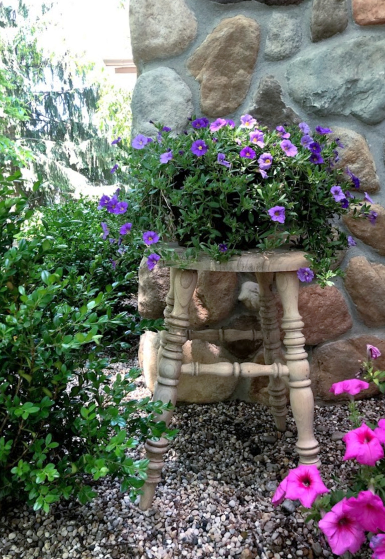 Rustic farmhouse wood stool in the garden with summer blooms - Hello Lovely Studio. #hellolovelystudio #gardenstool #rusticstool #summergarden #homedecor #outdoorstool