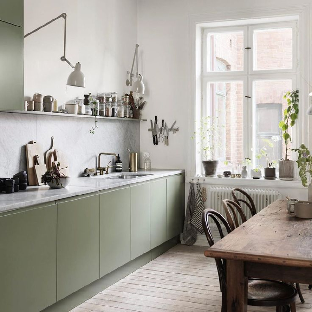 Serene sage green Scandinavian kitchen with mossy green cabinets and modern adjustable arm sconces - Petra Bindel. #swedishkitchen #scandinaviandesign #nordicstyle #europeancountry #kitchendesign