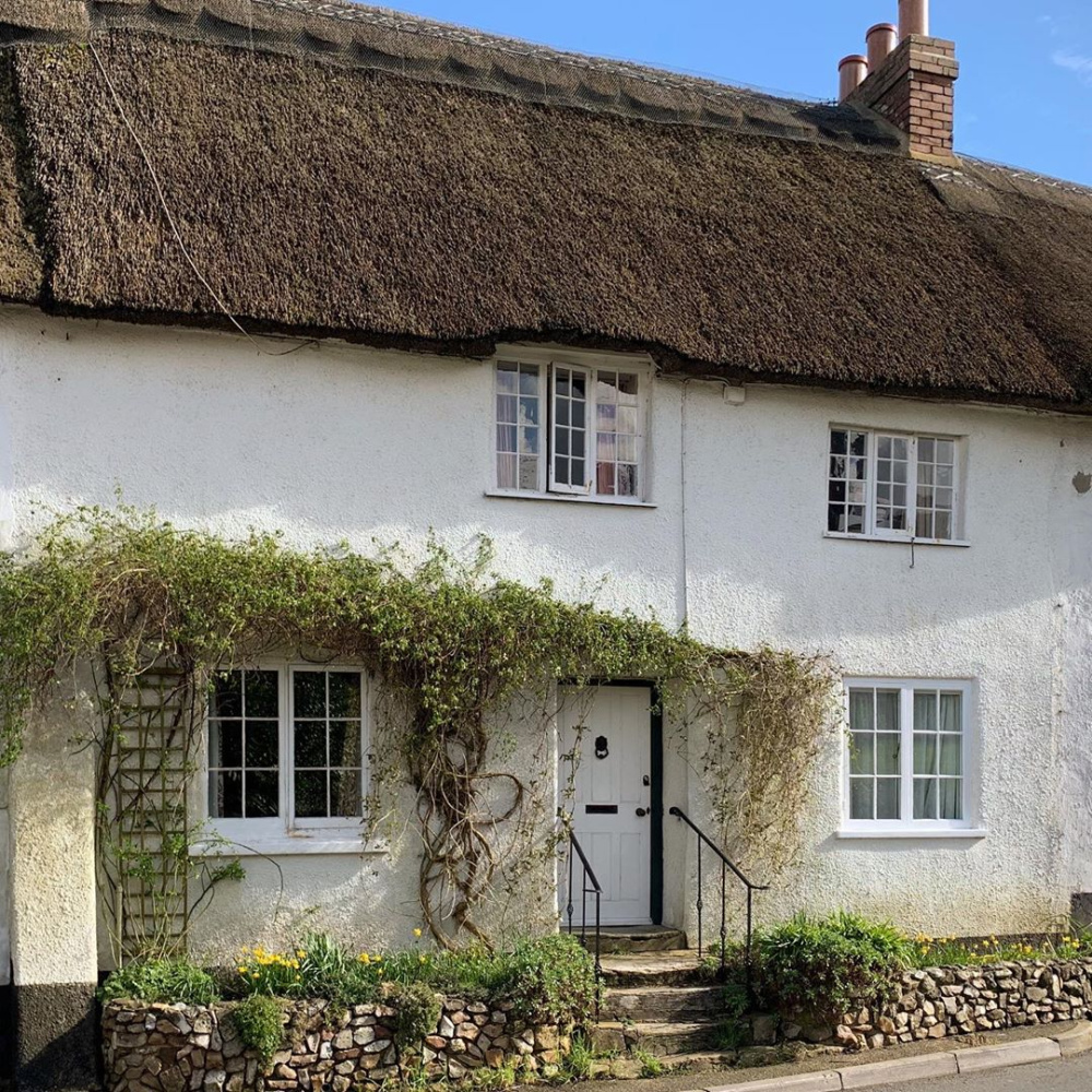 Charming white stucco English cottage home with thatched roof - Heart Felt Home.Charming inspiration if you love white painted house exteriors! #whitehouses #whitecottage #thatchedroof #englishcottage #whitestucco