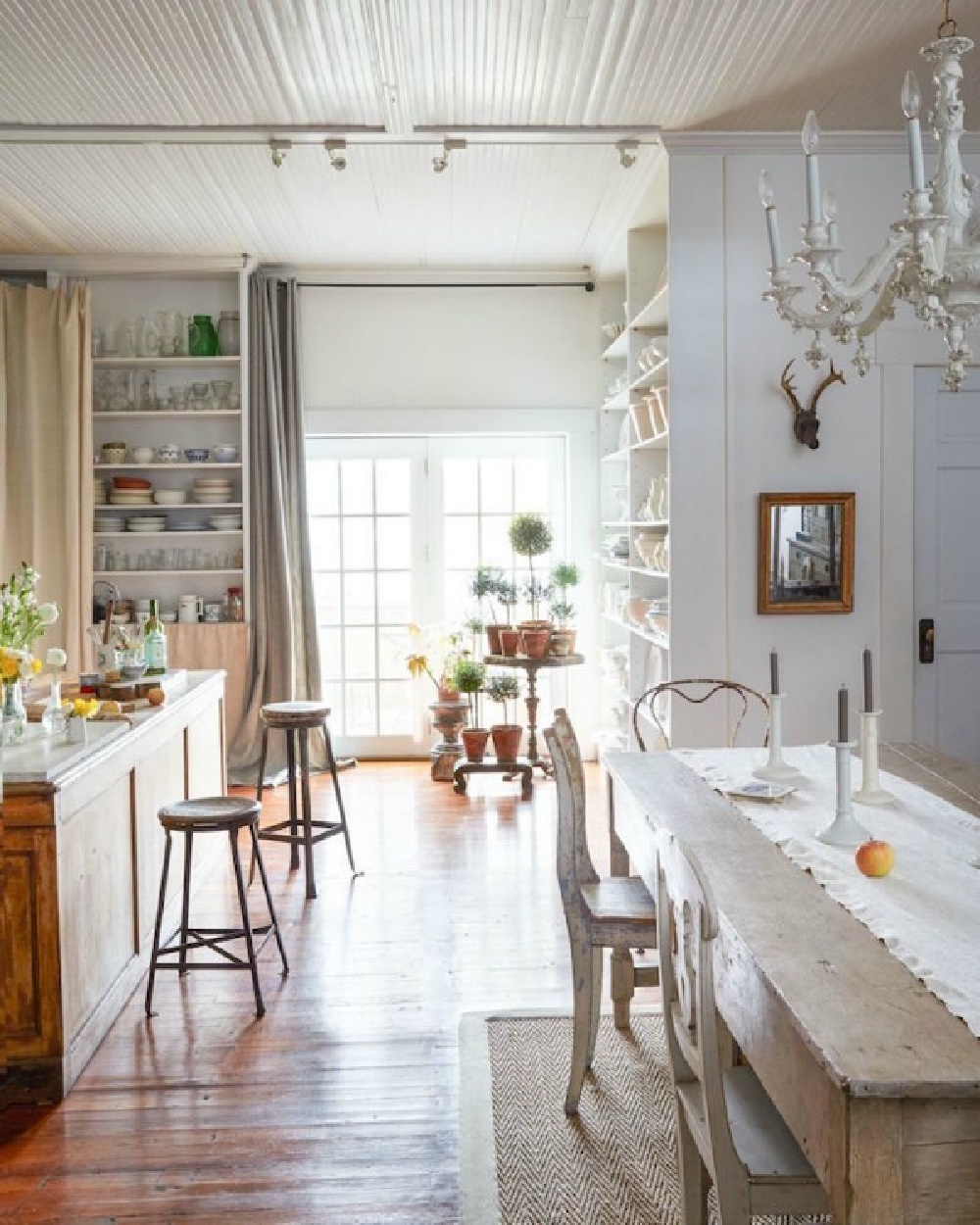 Quiet and humble beauty in a lovely country kitchen and dining area with shabby chic vintage style. A chunky antique farm table mixes with antique mismatched chairs and a white chandelier. #shabbychic #countrykitchen #beadboardceiling
