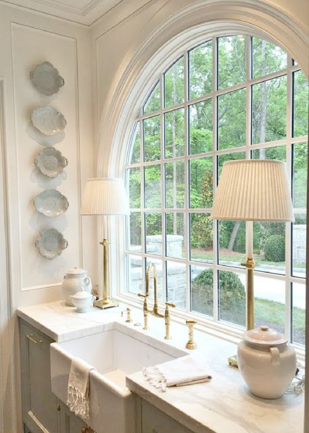 Elegant, refined, and masterfully designed, this kitchen with farm sink and arched window is but one moment in our tour of unforgettable interiors with European inspired charm. #farmsink #FrenchCountry #lightblue