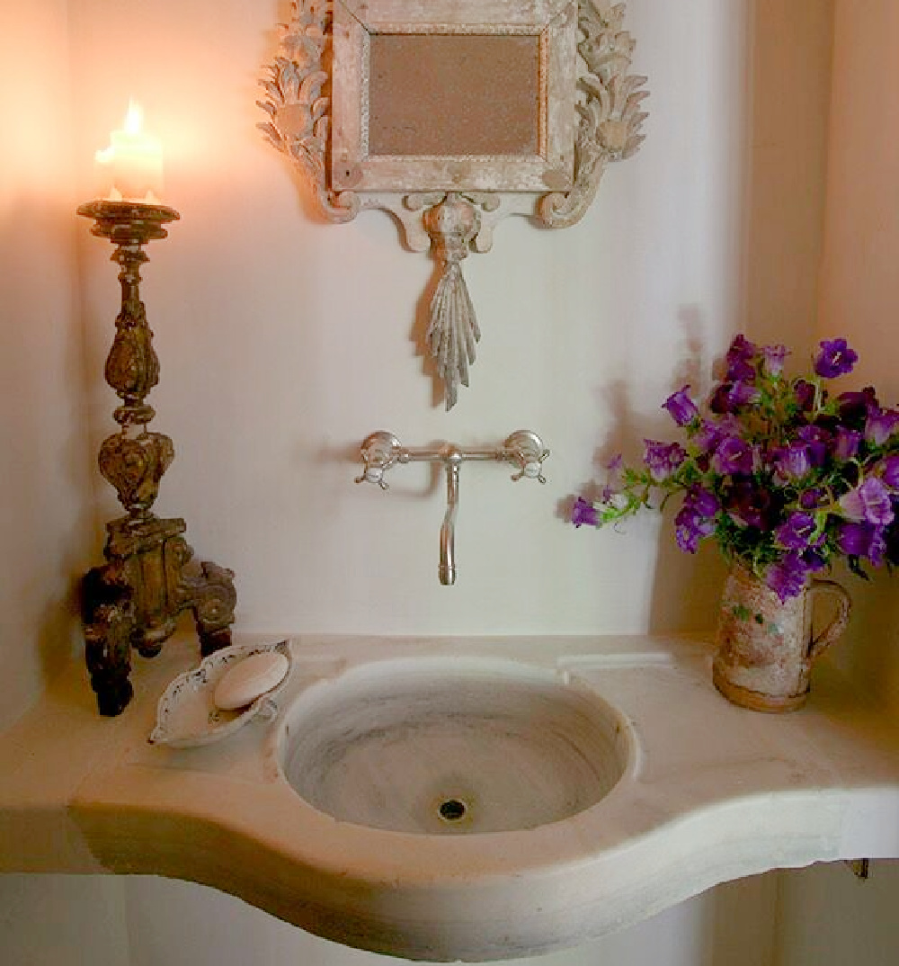 Antique stone sink, ancient candlestick and ornate mirror in a country French bath - Chateau Domingue.