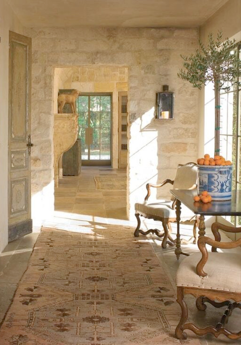 Rugged reclaimed stone walls and floor in a hall with treasures from Chateau Domingue - in Ruth Gay's exquisite French home.