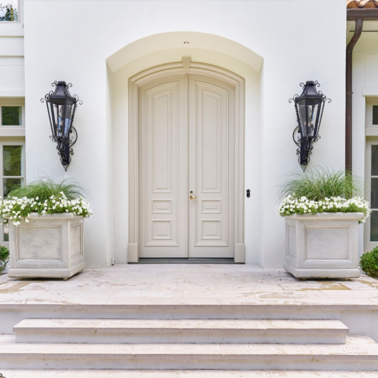 Breathtaking front door and entry to traditional style white stucco mansion in Buckhead. The 2020 Southeastern Designer Showhouse 'Villa Flora' is painted Benjamin Moore Seapearl and trim is Benjamin Moore Pashmina. #paintcolors #seapearl #benjaminmooreseapearl #pashmina #benjaminmoorepashmina #houseexteriors #housecolors