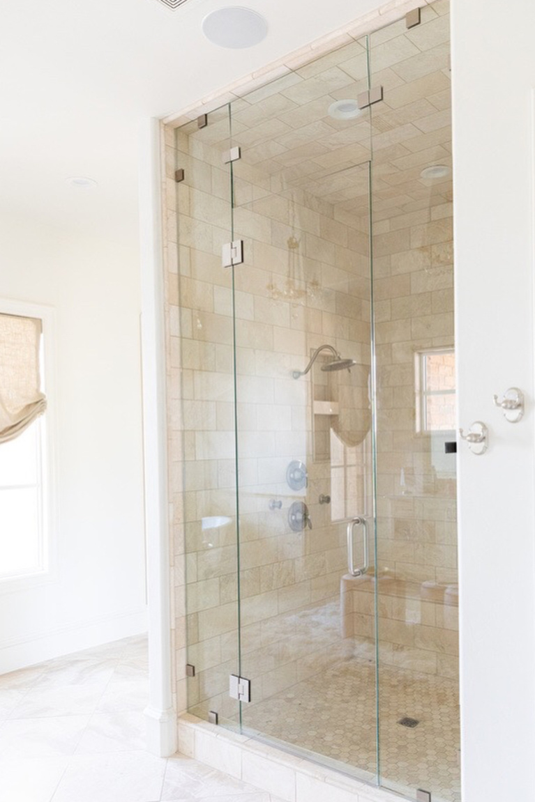 Stone tile in a shower within an elegant French country bathroom design by Brit Jones. #shower #bathroomdesign #frenchcountry #luxuriousbath