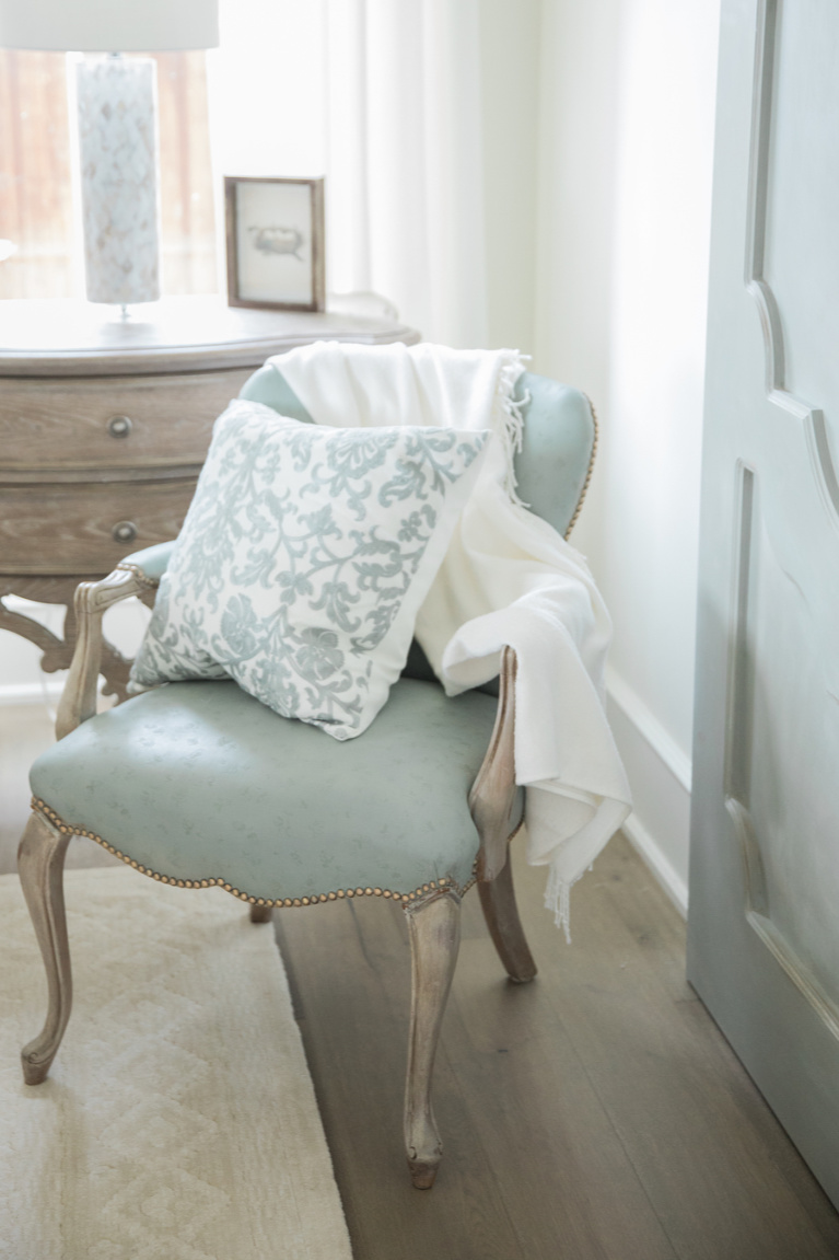 Duck egg blue upholstered arm chair and barn door in an elegant French country bedroom - Brit Jones. #duckeggblue #frenchcountry #bedroomdecor #barndoor #frenchfurniture