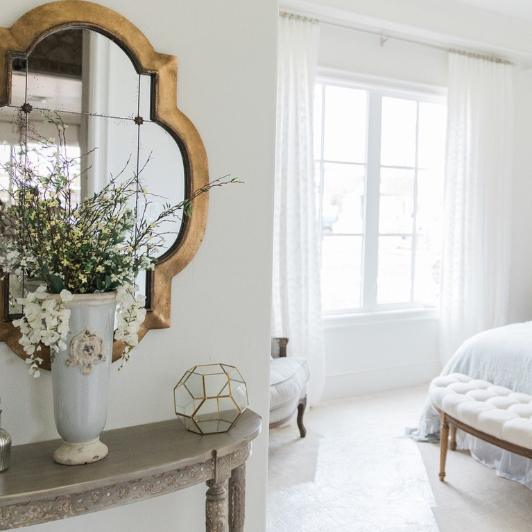 Elegant, romantic and serene French country bedroom with upholstered headboard and white drapes - Brit Jones. #interiordesign #romanticdecor #bedroomdecor #frenchcountry #whitebedrooms