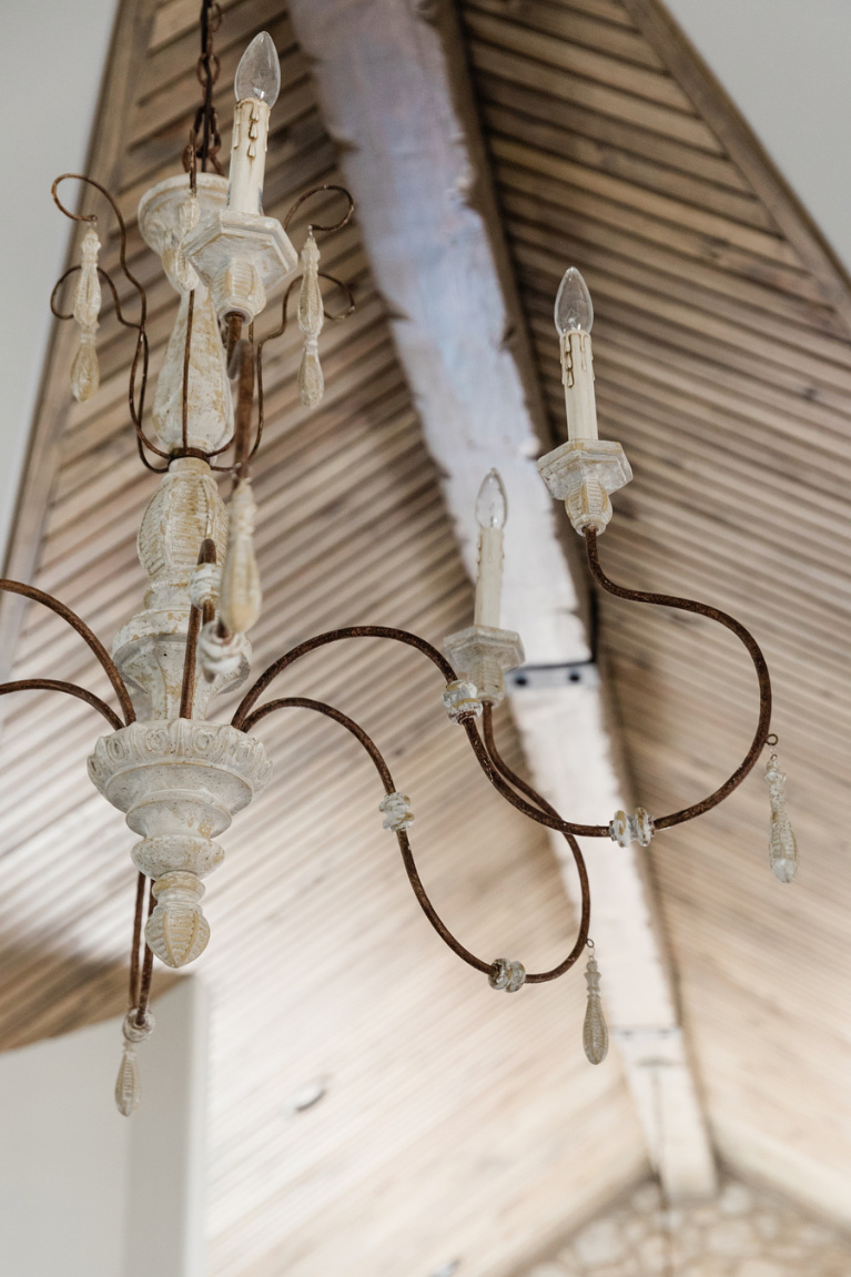 Rustic wood architectural ceiling with elegant Old World style French chandelier in romantic bedroom by Brit Jones. #romanticdecor #bedroomdesign #frenchcountry #chandelier #woodceiling