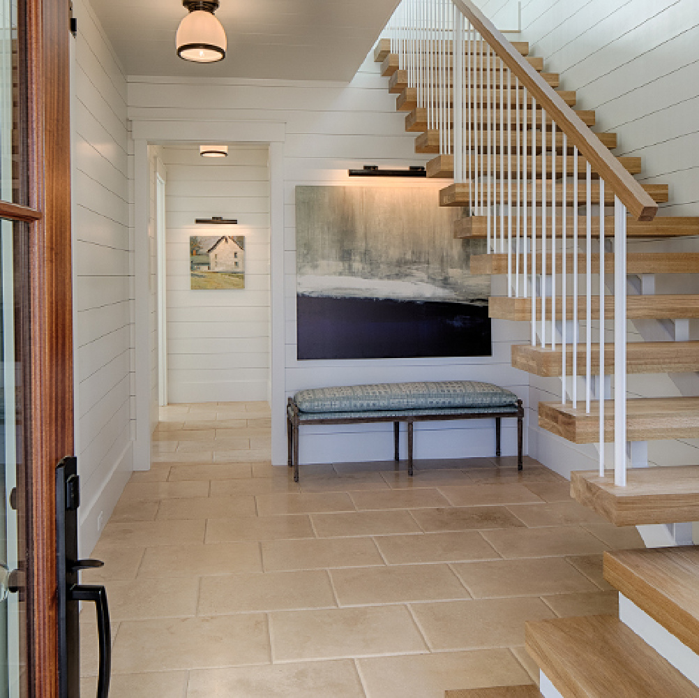 White oak hardwood flooring and floating staircase in entry.Board and batten coastal cottage in Palmetto Bluff with modern farmhouse interior design by Lisa Furey.