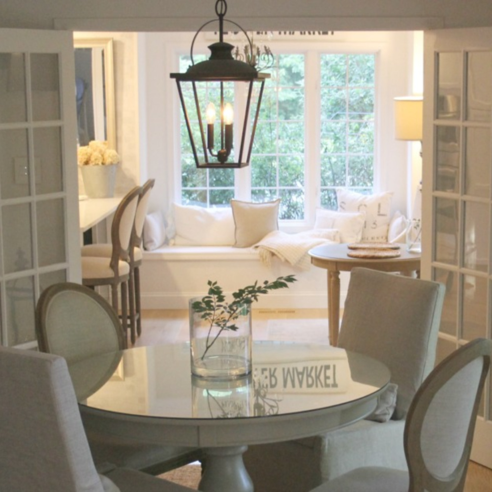 Cozy European country style dining room with vintage French doors leading to kitchen with window seat - Hello Lovely.